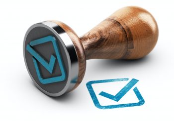 Check mark and rubber stamp over white background.